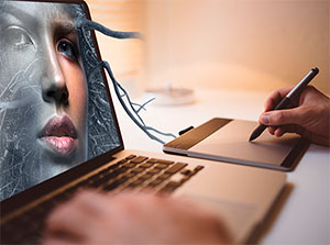 Ein Grafiker arbeitet an einem Laptop und retuschiert in Adobe PhotoShop ein Portraitbild – Adobe PhotoShop Schulung