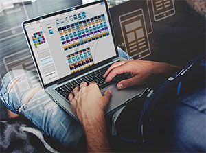 Ein Mann arbeitet an einem Laptop und verdrahtet in Adobe XD Screendesigns zu einem interaktiven Prototypen – Adobe XD Schulung